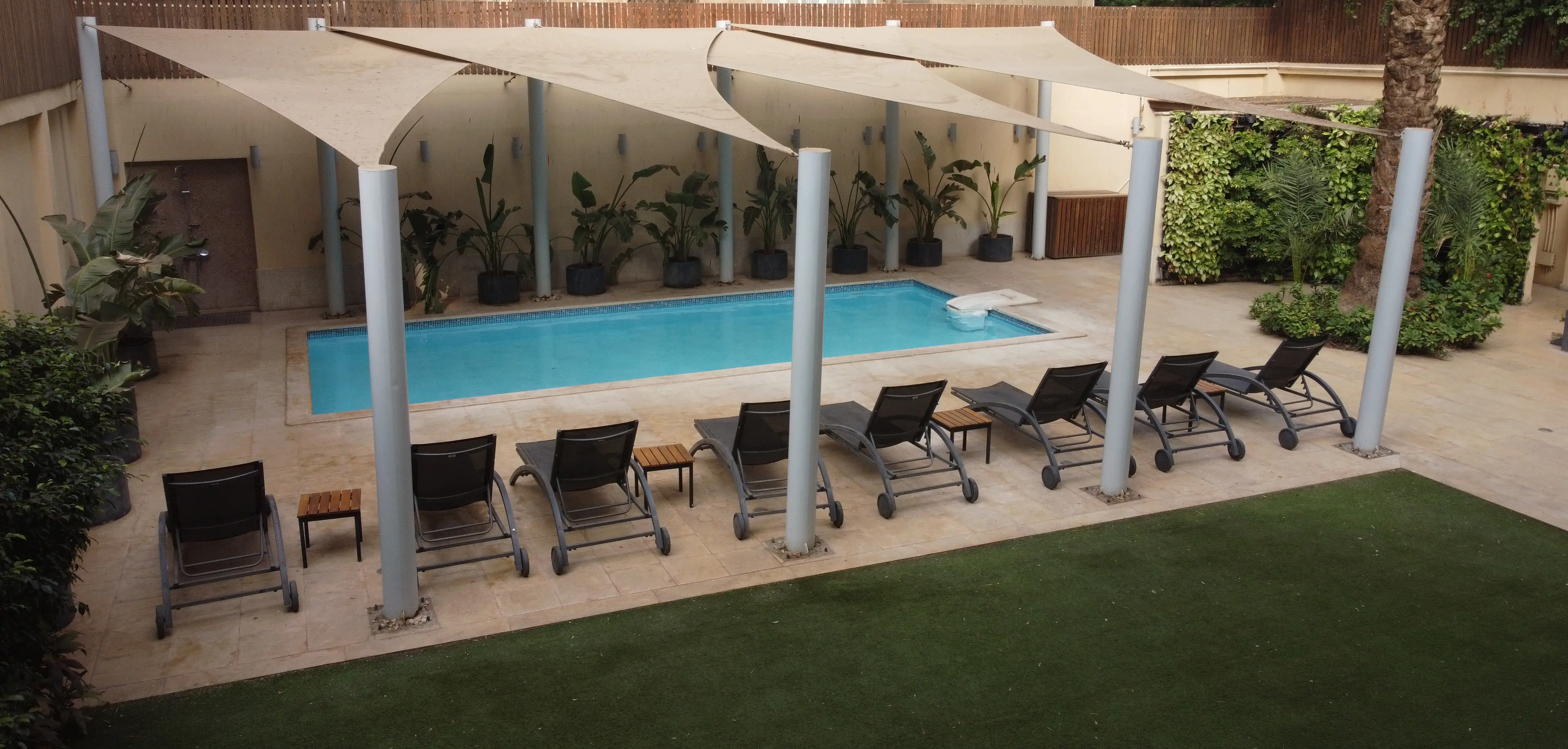 The outdoor pool at ICONIA Zamalek with shade sails and loungers